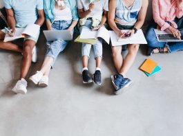 ritratto dall alto di giovani con laptop e smartphone seduti insieme sul pavimento studenti che scrivono lezioni tenendo i libri di testo sulle ginocchia